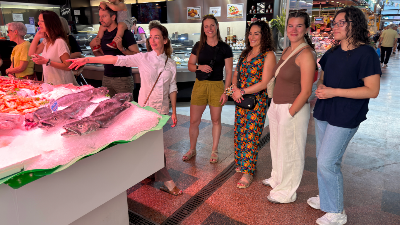 A group on a guided tour in front of a fresh fish stall at a Barcelona market